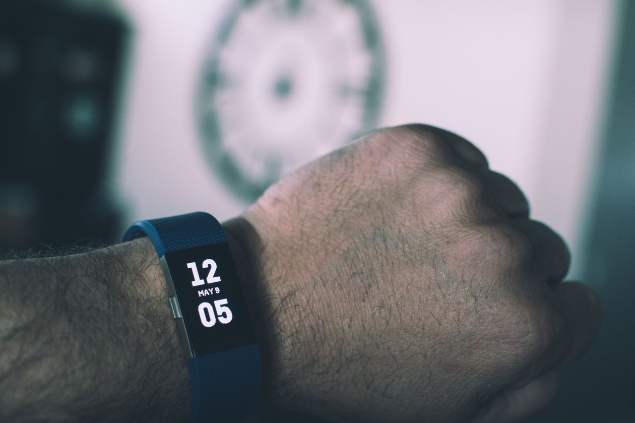 About Close-up of a digital smartwatch showing time and date on a man's wrist indoors.