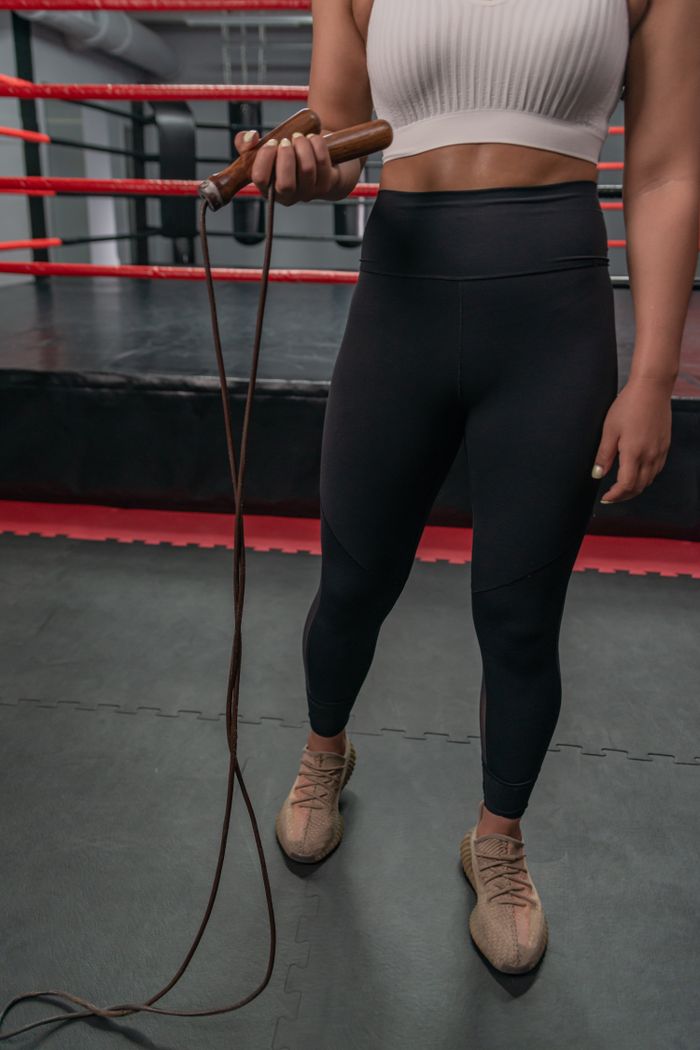 Mastering the First Impression: Your intriguing post title goes here Strong woman holding a jump rope in a boxing gym, showcasing fitness and strength.